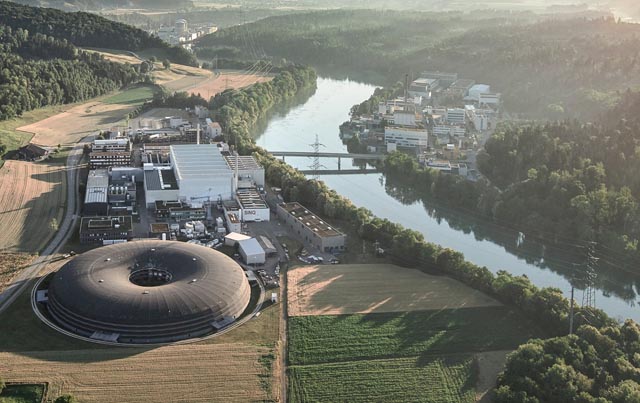 Das wohl markanteste Gebäude des PSI: Die SLS ist kreisrund, entsprechend dem Elektronenspeicherring von 288 Metern Umfang, der darin verläuft. Die auf knapp Lichtgeschwindigkeit beschleunigten Elektronen liefern an rund 20 Experimentierplätzen hochintensive Synchrotronstrahlung für die Forschung. Foto: Paul Scherrer Institut/Michel Jaussi Photography