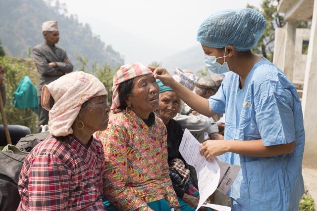 Eine medizinische Fachperson untersucht vor der Grauer-Star-Operation die Augen von verschiedenen Patientinnen. Foto: CBM